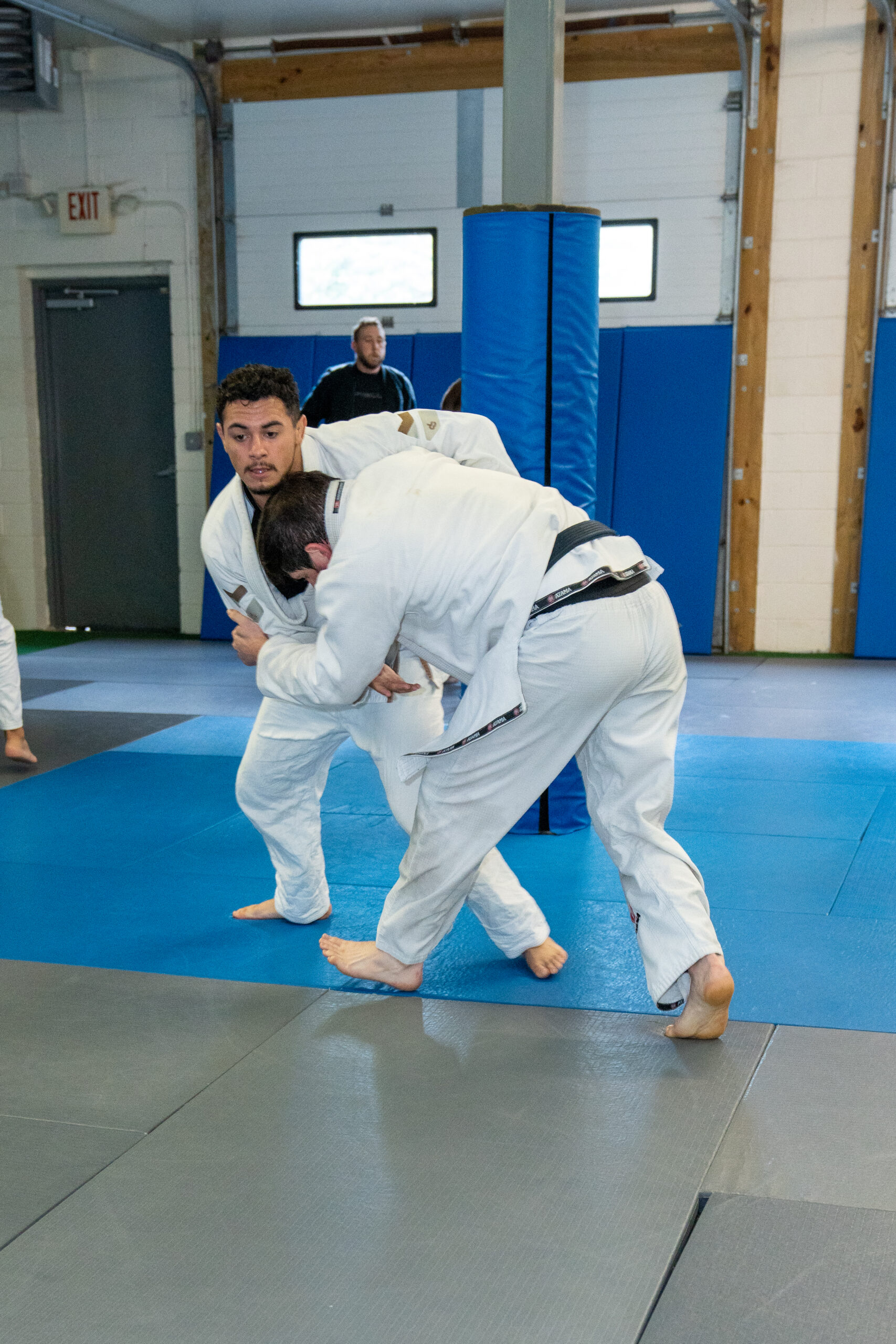 Students practicing a Brazilian Jiu-Jitsu clinch during live self-defense training, developing control, balance, and leverage.
